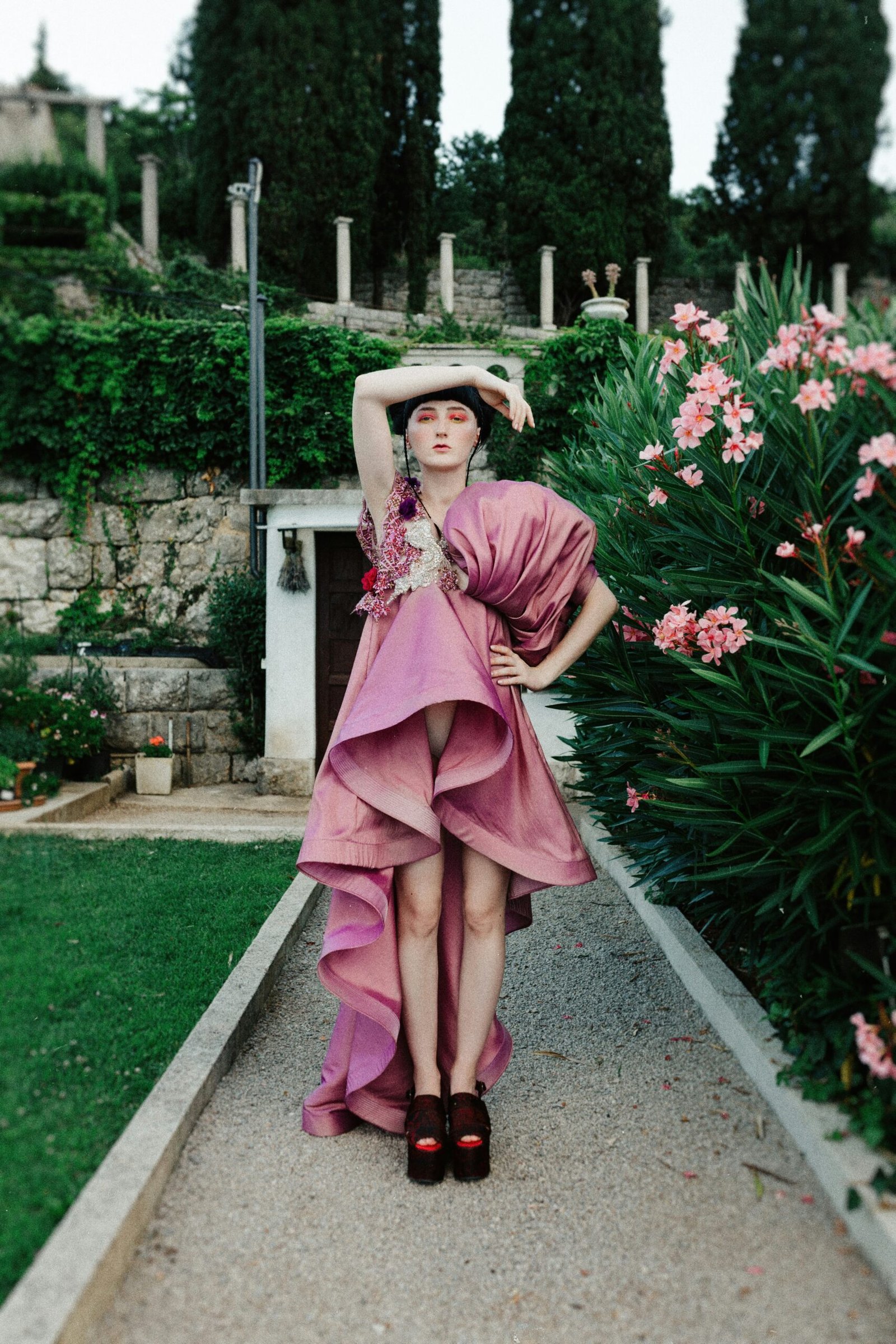 woman in pink dress and white hat standing on pathway